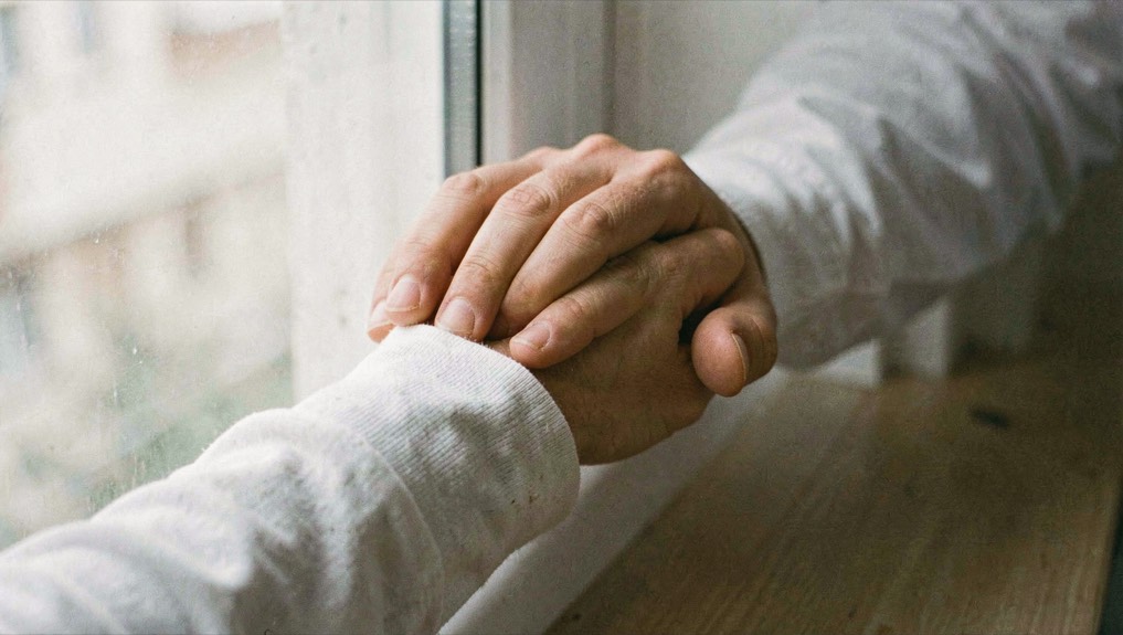 Two fingers resting on the inside of a wrist over a light cotton sleeve near a window